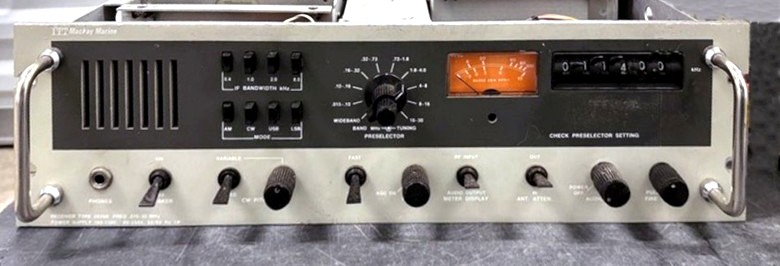 Light  beige receiver 5 inch by 19 inch with thumb-wheel switches to set frequency, S-Meter, speaker,  5 knobs and 5 toggle switches 